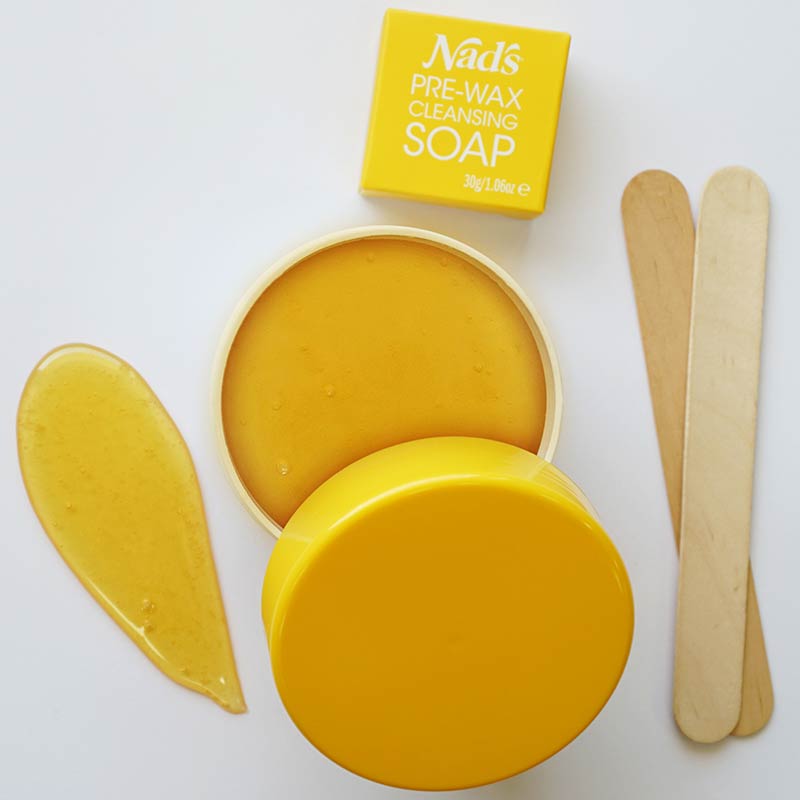 Nad's Natural Sugar Wax open container, smear of wax, pre-wax cleansing soap, and wooden applicators
